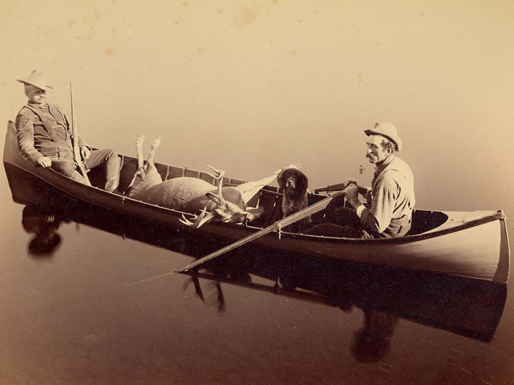 Seneca Ray Stoddard, Ed. McAlpin - más tarde General, c. 1890 El cazador McAlphin está sentado en la popa de la lancha guía. Su guía, Jack Richards, está sentado en la proa junto a un perro de caza. (P019986)