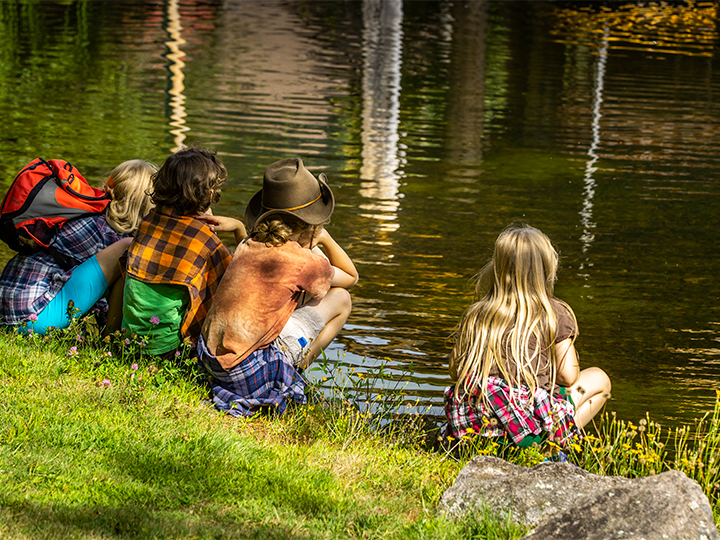 Un grupo de niños visita el ADKX y observa los peces frente al Pabellón de Transporte del Río Marion.