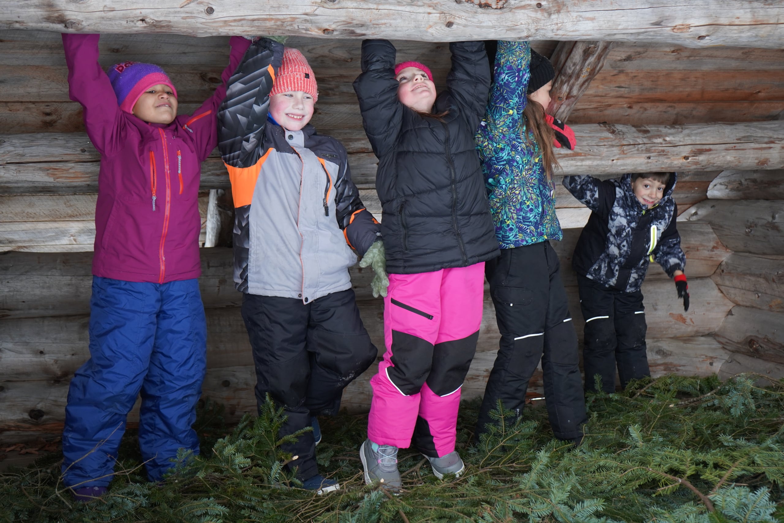 kids in snowsuits playing in a lean-to