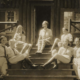 A group of six children are sitting on a porch, posing for a picture.