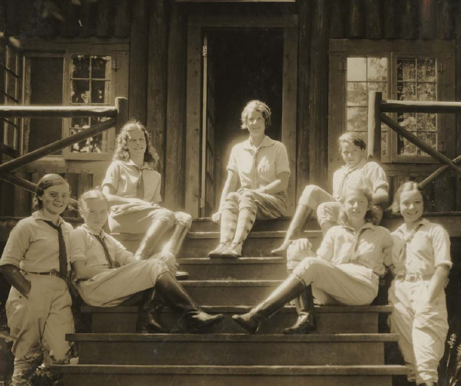 A group of six children are sitting on a porch, posing for a picture.