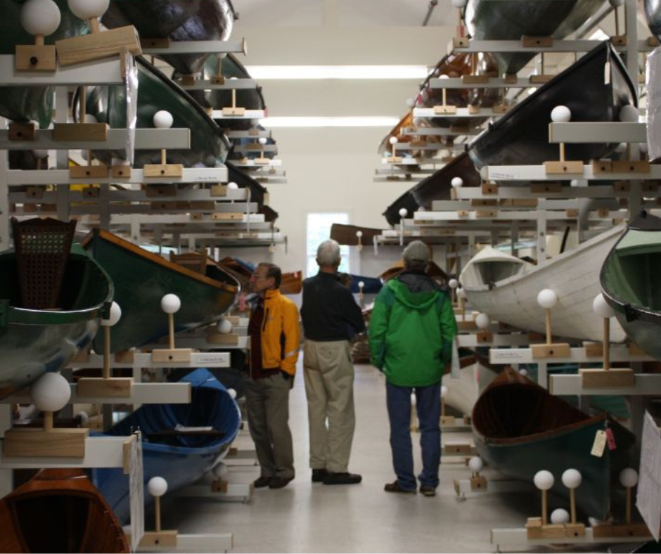 Three men are standing in a room with a large number of boats.