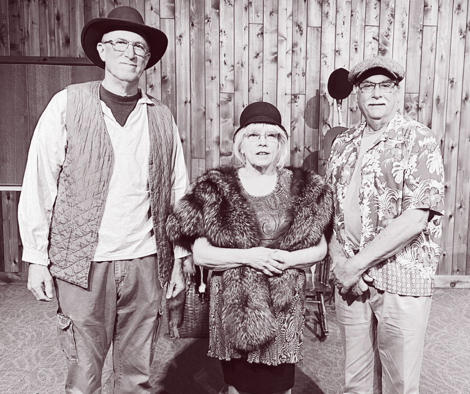 Tres personas posan para una foto, dos hombres y una mujer. La mujer lleva un abrigo de piel y los hombres, sombreros.